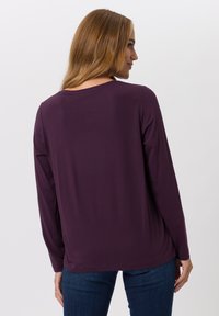 Paarse langemouwshirt met een ronde halslijn en een zachte, gladde textuur, voorzien van een relaxed fit en een gebogen zoom.