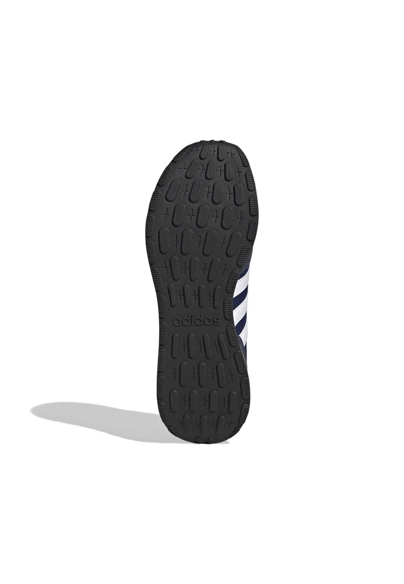 Schwarze Gummisohle mit strukturiertem Muster für Griff, mit dezentem Adidas-Branding. Die Seite hat navy- und weiße Streifen für gestalterische Kontinuität.