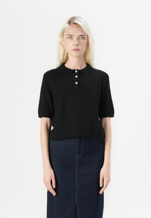 Black short-sleeved polo top with a collar and three white buttons, paired with a dark denim skirt featuring a front slit.