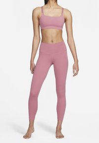 Ljust rosa sport-bh med fyrkantig halsringning och justerbara axelband, i kombination med högmidjade, figurnära leggings i samma färg.