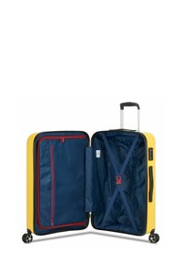 Gele harde koffer met zilveren handgreep en zwarte wielen; interieur met marinevoering, rode ritssluitingzak en blauwe beveiligingsriemen.