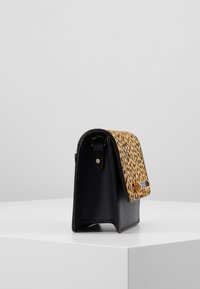 Borsa in pelle nera con un cappuccio a stampa leopardata, dotata di una fibbia laterale e una texture liscia, forma strutturata e dettagli a contrasto.