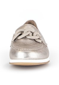Metalen zilveren instapschoenen met een gestructureerde afwerking, voorzien van een grote beige kettingaccent op de bovenkant en een witte rubberen zool.