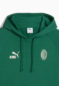 Groene hoodie van zachte stof met een kangoeroezak, trekkoordcapuchon, Puma-logo, "KING" tekst en AC Milan-embleem in het wit.