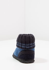 Bottine en mélange de laine avec un revers tricoté gris foncé, un corps en feutre bleu et une semelle noire. Présente un design incurvé et des motifs de tissu texturé.