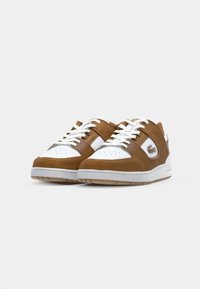Brown and white sneakers with a mix of smooth and suede textures, featuring a perforated toe, laces, and a logo on the side.