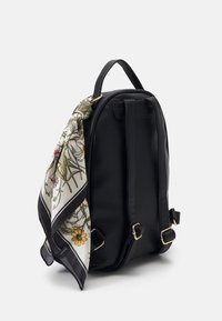 Schwarzer Leder-Rucksack mit strukturierter Oberfläche, zwei Trägern und einem dekorativen, blumigen Seidenschal, der seitlich gebunden ist. Akzente aus goldfarbenem Metall.