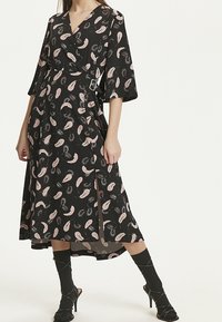 Svart omlottklänning med rosa fjädermönster, breda ärmar, hög slits och accentrem. Slät material med en flödande design.