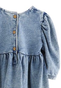 Abito in denim con scollatura rotonda, maniche a sbuffo, vita arricciata e chiusure con bottoni in legno sul retro. Colore azzurro chiaro con una finitura testurizzata.