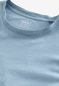Tricou din bumbac de culoare albastră deschisă, cu guler rotund, croială regulată și tiv cusut. Previne eticheta "NEXT" și instrucțiunile de întreținere imprimate în interior.
