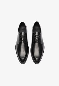 Černé kožené společenské boty s hladkým povrchem, špičatou špičkou, šněrovacím designem a minimalistickou estetikou. Žádné viditelné loga ani vzory.