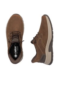 Zapatos de cuero marrón con un acabado texturizado, que cuentan con cordones oscuros, un collar acolchado y una suela acolchada con acentos en gris claro.