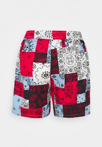Shorts en patchwork multicolores avec des motifs de bandana rouge, noir, bleu et blanc, dotés d'une taille élastique pour plus de confort.