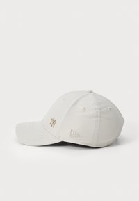 Casquette de baseball gris clair avec logo NY brodé et patch sur le côté, dotée d'une visière courbée et d'une finition en tissu texturé.
