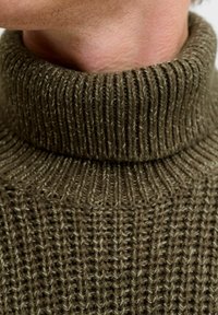 Maglione polo verde lavorato a maglia con un motivo a coste testurizzate, caratterizzato da un colletto alto e un materiale morbido e voluminoso.