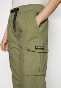 Olijfgroene cargobroek gemaakt van lichtgewicht stof, met een cordon in de taille, zijzakken en een patch met merkdetails.