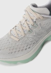 Baskets de course en maille gris clair avec des lacets beiges, des accents vert menthe et une tige transparente à motif sur fond blanc.