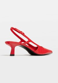Chaussure rouge slingback à talon kitten avec bout pointu et motif texturé sur fond blanc.