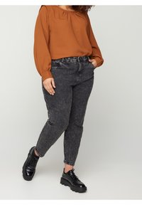 Blusa marrone a maniche lunghe con scollo plissettato, abbinata a jeans in denim neri a vita alta e scarpe stringate nere chunky.