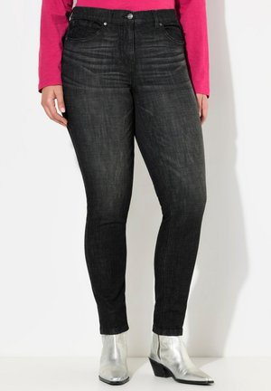 Černé džíny skinny mají klasický design s pěti kapsami, jemné vyblednutí a střední pas. Kombinují se se stříbrnými kotníkovými botami.