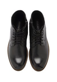 Botas de tobillo de cuero negro con un acabado suave y pulido, diseño con cordones, cremalleras laterales y una suela texturizada marrón. Etiqueta de marca visible en el interior.