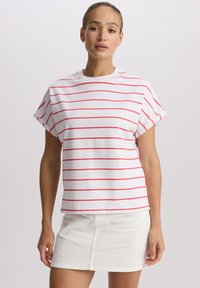 Biały t-shirt z krótkim rękawem i czerwonymi poziomymi paskami, z okrągłym dekoltem i podwiniętymi mankietami, zestawiony z białą denimową spódnicą.