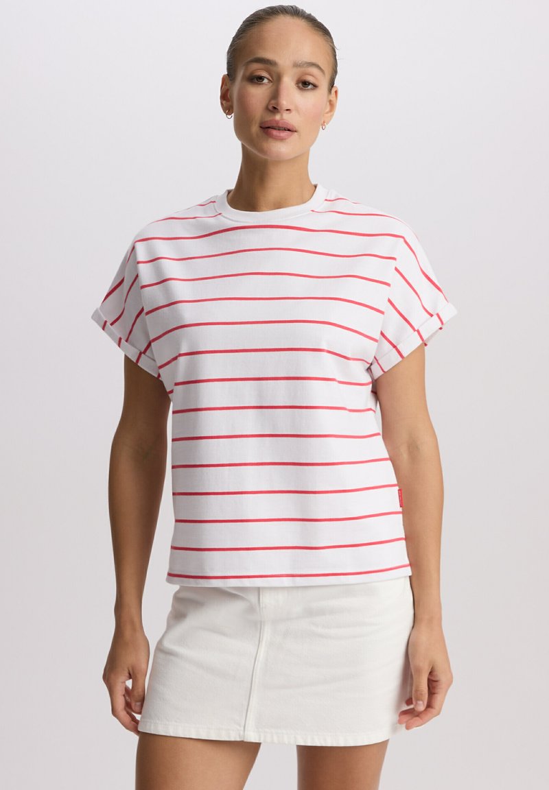 Biały t-shirt z krótkim rękawem i czerwonymi poziomymi paskami, z okrągłym dekoltem i podwiniętymi mankietami, zestawiony z białą denimową spódnicą.