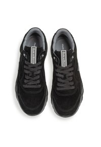 Schwarze Wildledersneakers mit grauen Akzenten, runden Schnürsenkeln und einem gepolsterten Kragen. Auffälliges Logo-Detail auf der Zunge.