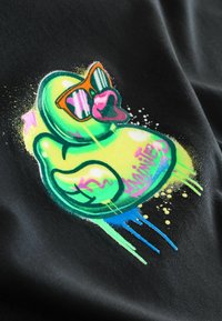 Grafisches T-Shirt mit einem bunten Cartoon-Gummienten-Motiv mit Sonnenbrille in neon-grünen und -roten Farbtönen auf einem schwarzen Stoffhintergrund.