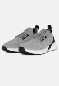 Grå stickade sneakers med en strukturerad yta, svarta accenter och en vit sula. Har flexibla snören och en dragrem för enkel användning.