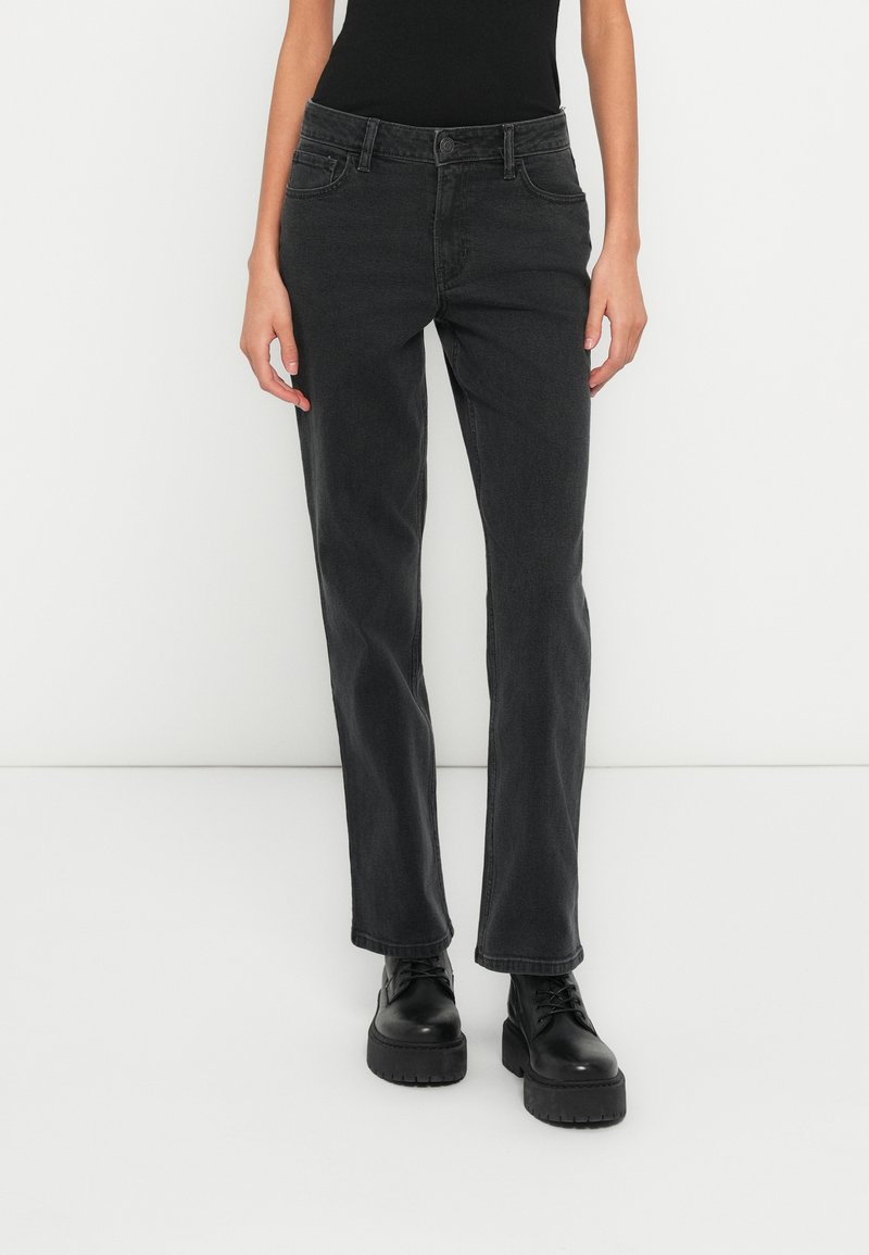 Čierne riflové nohavice s rovným strihom nohavíc, dizajnom s piatimi vreckami a jemným prešitím. Doplnkom sú čierne robustné bojové topánky.