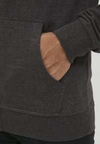 Gray sweatshirt featuring a front pocket, ribbed cuffs, and hem. Soft texture with a logo accent near the pocket.