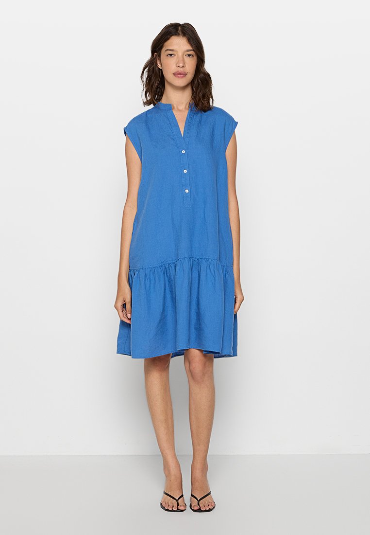 Niebieska lniana sukienka z guzikami z przodu, z krótkimi rękawkami i marszczonym, warstwowym dołem. Gładka struktura i luźny krój.