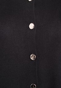 Čierny pletený sveter so striebornými gombíkmi pozdĺž prednej časti. Materiál má jemnú, hladkú textúru s rebrovanými detailmi.