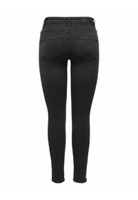 Mustad kitsad teksad kõrge vöökohaga, viie tasku disainiga ja siledapinnaline. Omavad standardset tagumist taskute paigutust ja puudub nähtav bränding.