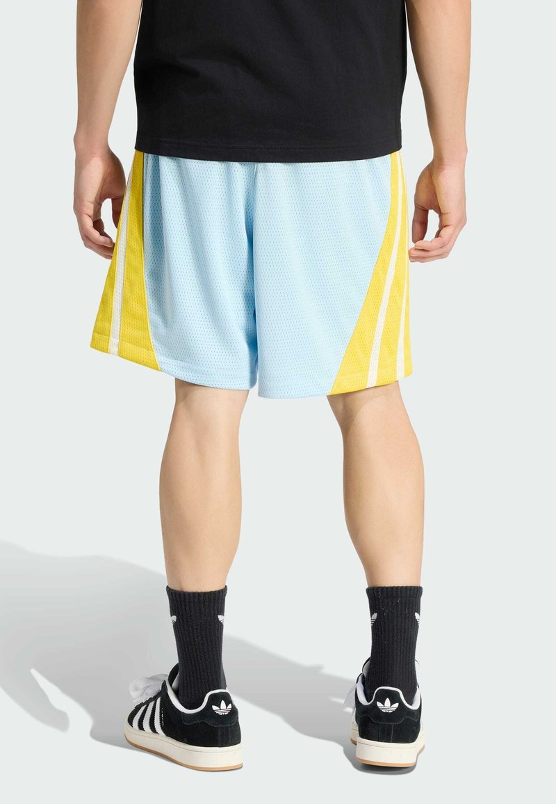 Shorts de basketball en maille bleue avec des rayures jaunes, dotés d'une taille élastique, assortis à des chaussettes noires côtelées et des baskets Adidas noires.