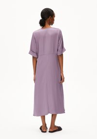 Lavender midi dress with short rolled sleeves, straight cut, and back seam detail. Made of lightweight fabric with a smooth texture.