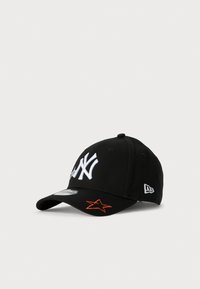 Fekete baseball sapka fehér "NY" logóval az elején, fehér márkalogóval az oldalon, és narancssárga csillaggal a karimán.