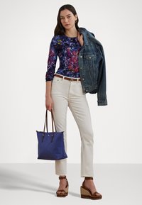 Cvečni top z dolgimi rokavi, beli ravni kavbojke, jeans jakna prek rame, rjav pas, modra torbica, rjave sandalske pete.
