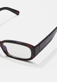 Tortoise shell mintás szemüveg, téglalap alakú lencsékkel, műanyag kerettel, enyhén ívelt szárakkal és átlátszó lencsékkel. Simább tapintás, fényes felülettel.