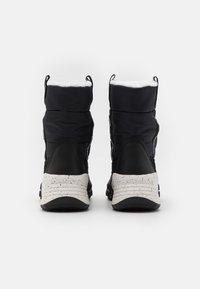 Czarne ocieplane botki z puchową górną częścią z nylonu, białą podszewką z sztucznego futra oraz nakrapianą gumową podeszwą. Widok z tyłu ukazuje podwójne pętelki do zakładania.