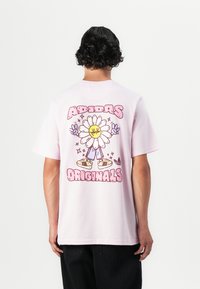 Rosa Baumwoll-T-Shirt mit buntem Cartoon-Blumenmotiv auf der Rückseite und dem Text "ADIDAS ORIGINALS" darunter, mit kurzen Ärmeln und lässiger Passform.