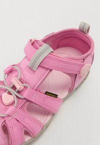 Pink washable sandal with multiple adjustable straps, a textured sole, and a pull tab at the heel. Features grey accents and elastic lacing.