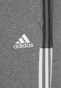 Grijze sweatshirt met witte geborduurde "adidas" logo. Bevat een zwart-wit gestreepte accent aan de zijkant, met een zachte stoftextuur.