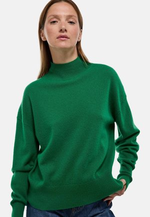 Pull vert avec un col montant, coupe ample et poignets et ourlet côtelés. Fabriqué en matière douce, affichant une texture lisse.