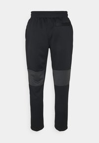 Černé sportovní kalhoty se zúženým střihem, které mají světlé šedé panely na kolenou a kapsy na bocích a vzadu. Elastický pas.