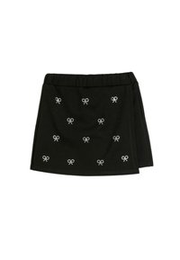 Jupe mini noire avec une taille élastique et des motifs de nœuds en strass éparpillés. Le tissu semble doux avec une texture lisse.