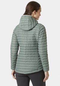 Světlě zelená péřová bunda s kapucí, která má prošívanou texturu, horizontální steh a přiléhavý střih. Zadní pohled ukazuje detaily švů.
