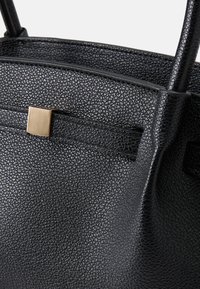 Black textured leather handbag with a smooth finish, featuring a golden rectangular clasp and two sturdy shoulder straps.