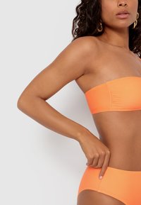 Oranžový bandeau bikiny top s rovnako farebnými vysokými spodkami. Hladká, elastická tkanina s priliehavým dizajnom a minimálnymi švovými detailmi.